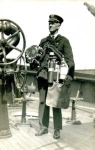 Lieutenant John Williams demonstrating a diver's mask and breathing apparatus, circa 1915.